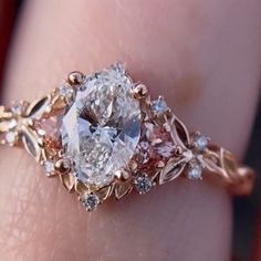 a close up of a person's hand holding a ring with a diamond in it