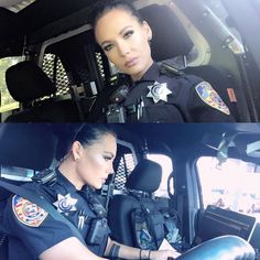 two police officers sitting in the back seat of a car, one is looking at the camera