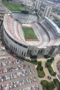 an aerial view of a football stadium with cars parked in the parking lot and buildings behind it