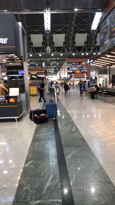 people are walking through an airport with their suitcases on the ground in front of them