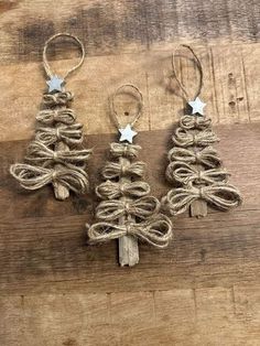 three small christmas trees made out of twine on a wooden table with silver stars