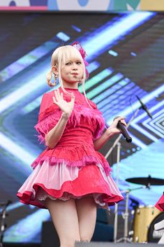 a girl in a red dress is on stage with her hand up to the side