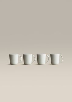 four white cups are lined up in a row on a gray background, with one empty cup to the side