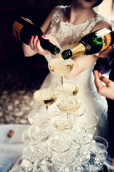 the bride and groom are pouring champagne into wine glasses on top of each other at their wedding reception