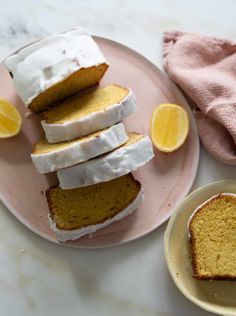 slices of lemon pound cake on pink plates with white frosting and sliced lemons