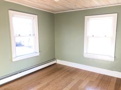 an empty room with two windows and hard wood flooring on the side of the room