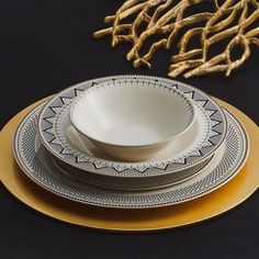 a set of four white and gold dinner plates on a black surface with golden accents