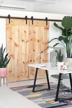 a white desk sitting in front of a wooden door next to a potted plant