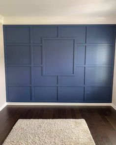 an empty room with wood floors and blue paneling on the wall, along with a white rug