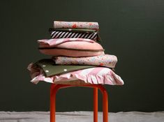 a stack of pillows sitting on top of an orange stool