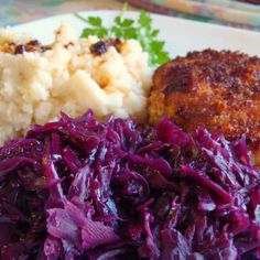 a white plate topped with meat, mashed potatoes and red cabbage