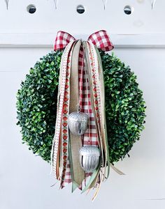 a christmas wreath with two silver bells hanging from it