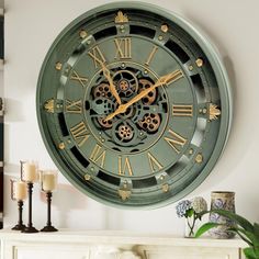 a large green clock on the wall above a mantel with candles and vases