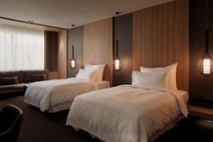 two beds in a hotel room with white linens and pillows on the headboards