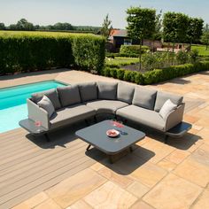 a couch and table on a patio next to a swimming pool