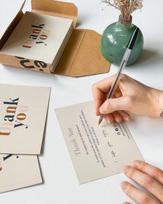 a person is writing on some cards with a pen and paper in front of them