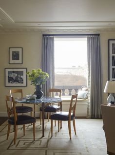 a dining room table with chairs and a vase filled with flowers on top of it