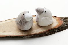 two stuffed animals sitting on top of a wooden slice