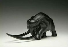 an elephant figurine is shown on a white surface with black accents and long tusks