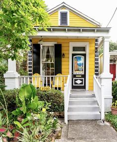 a yellow house with black shutters on the front door and steps leading up to it