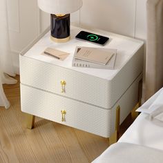 a bedside table with a book, lamp and phone on it