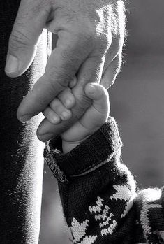 a black and white photo of a person holding the hand of a child's hand