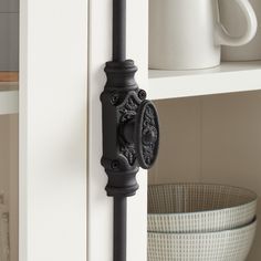 a close up of a door handle on a white cabinet with a basket in the background