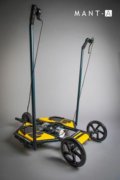 a yellow and black cart sitting on top of a gray floor next to two poles