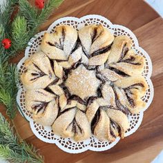 a pastry on a wooden platter surrounded by greenery and red berry sprigs