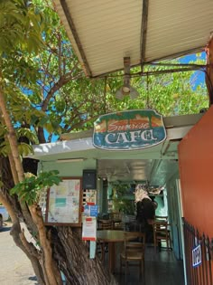 the outside of a cafe with tables and chairs under a shade umbrella over an outdoor dining area