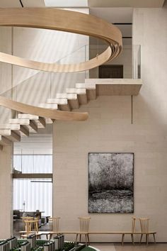 a spiral staircase in the middle of a living room with chairs and tables underneath it