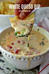 a hand dipping a tortilla chip into a white quesadilla dip