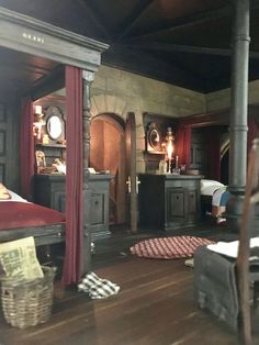 an old fashioned bedroom with wood floors and red drapes on the windowsills