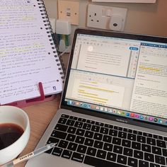 an open laptop computer sitting on top of a desk next to a cup of coffee