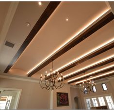 a chandelier hanging from the ceiling in a room with white walls and wood beams