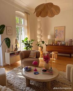 a living room filled with furniture and lots of plants on top of a rug in front of a window