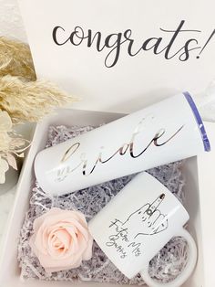 a white coffee mug and pink rose in a gift box with congratulations written on it