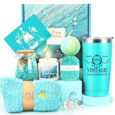 a blue gift box containing a candle, teal towels, and personal care items