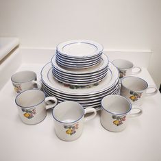 a stack of plates and cups sitting on top of a table