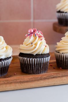 three chocolate cupcakes with white frosting and sprinkles on top