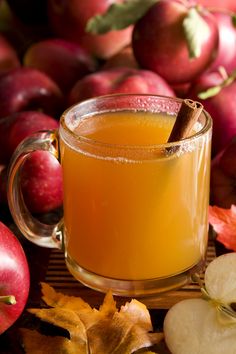 a glass mug filled with apple cider next to apples