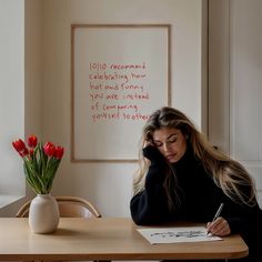 a woman sitting at a table with a pen and paper in front of her face