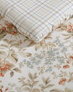 two pillows sitting next to each other on top of a floral print bed coverlet