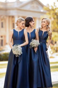 three bridesmaids in blue dresses standing together and smiling at each other with their bouquets