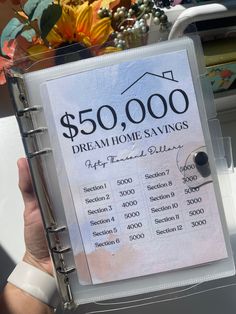 a person holding up a $ 500, 000 dream home savings binder