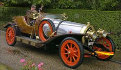 an old fashioned car is parked on the side of the road in front of some bushes