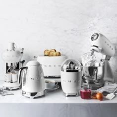 an assortment of kitchen appliances sitting on a counter top next to some fruit and bread