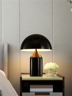 a black and gold lamp sitting on top of a table next to a white flower