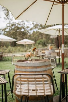 an outdoor dining area with tables, chairs and umbrellas on the grass in front of it