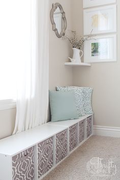 a white bench sitting next to a window in a room with curtains on the windowsill